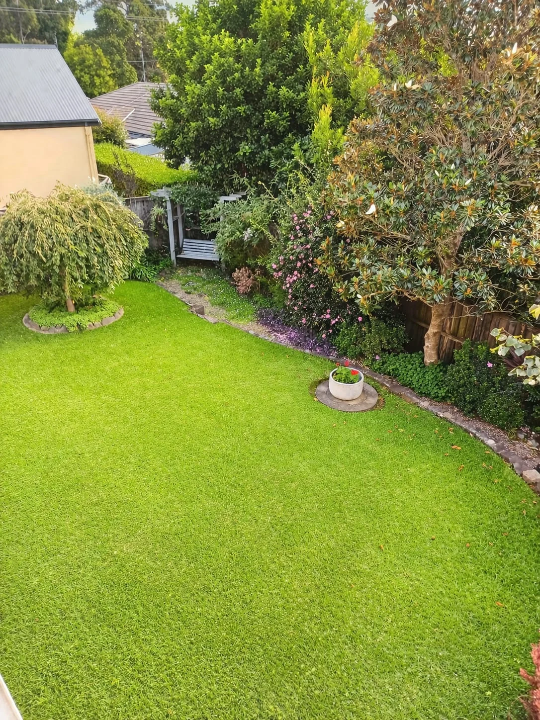Private garden at The Gables Berry with lawn, planted beds and a bench beneath an arbour